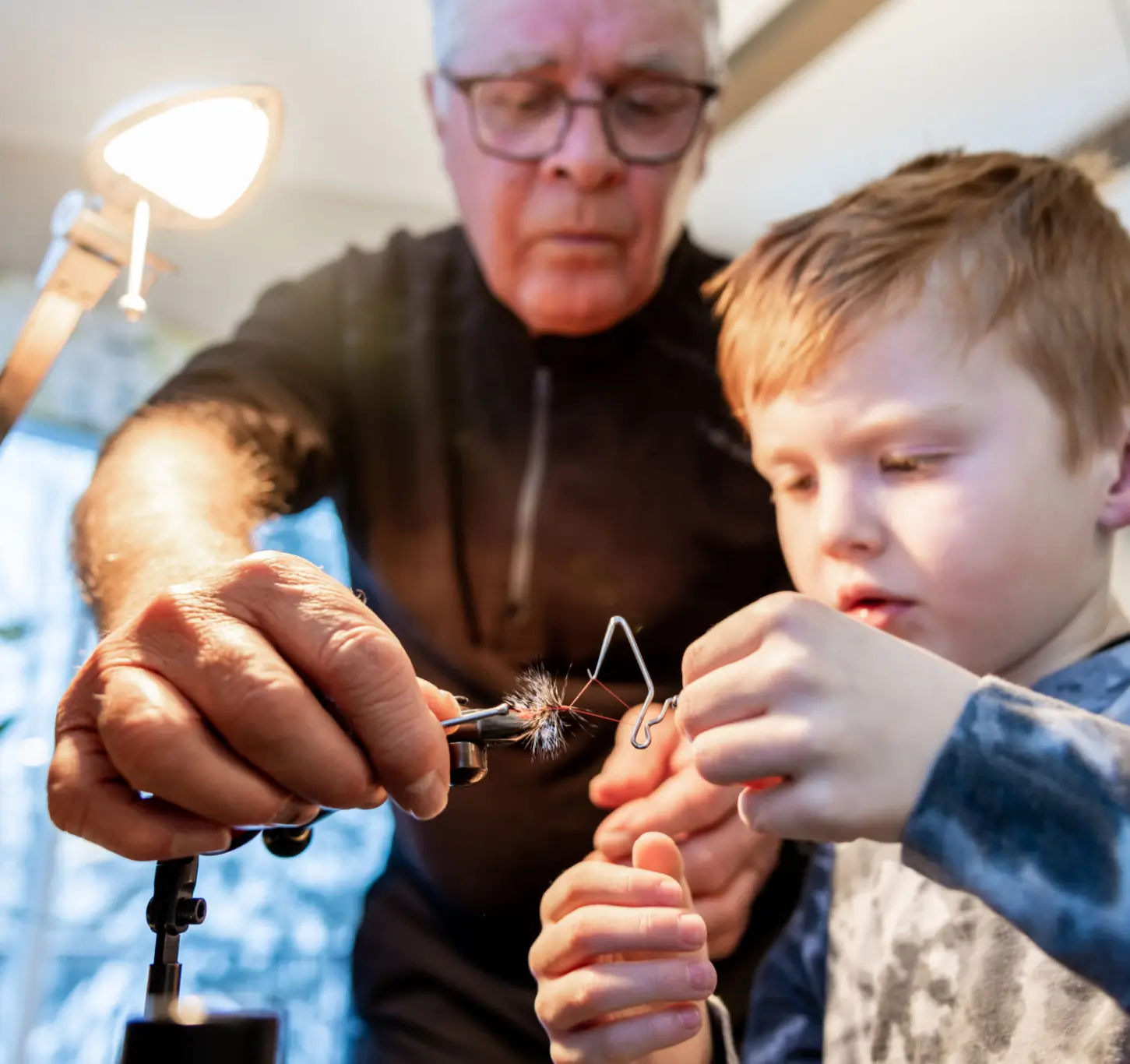 Man teaching boy fly fishing techniques.
