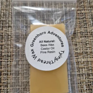 A sealed bag of light-colored beeswax beads on a textured fabric surface.